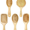 A collection of five wooden bamboo hair brushes with natural bristles shown against a white background.