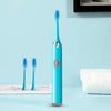 A blue sonic electric toothbrush with a replaceable head standing upright on a light blue surface.