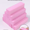 A stack of pink manicure sponge sanding blocks, showing various sizes and a hand holding one block.