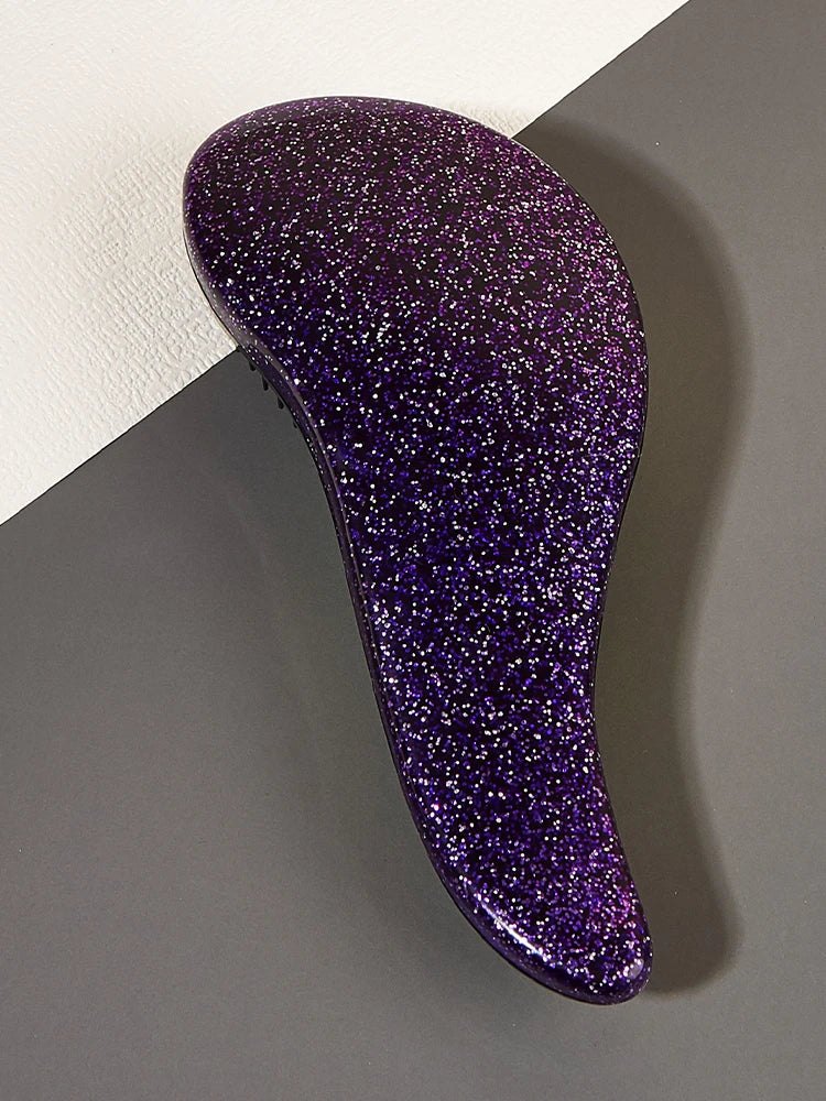 A purple, glittery duster brush is shown against a gray background.