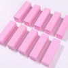 A row of pink nail buffer blocks arranged diagonally on a white surface.