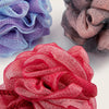 A close-up of exfoliating mesh bath sponges in shades of purple, gray, and red