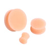 Three round, peach-colored silicone ear tunnels or plugs are shown against a white background.