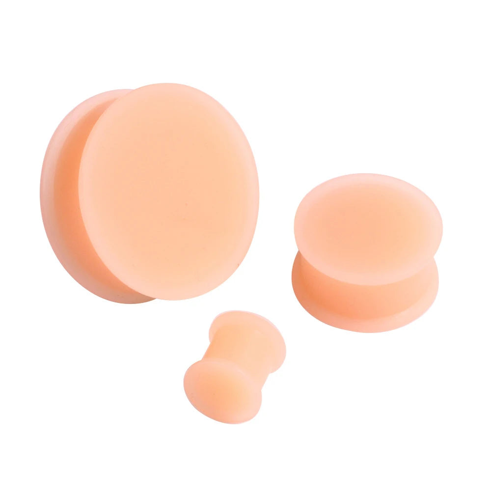 Three round, peach-colored silicone ear tunnels or plugs are shown against a white background.