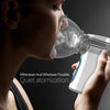 A person is using a white handheld mesh nebulizer to receive quiet atomization.