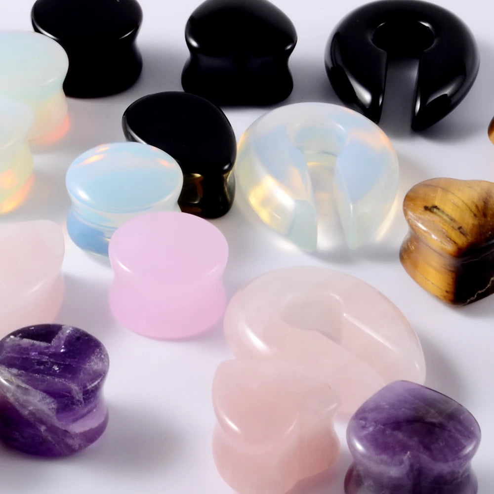 Colección de dilatadores para piercing en forma de oreja de piedra pulida en tonos morados, rosas y negros.