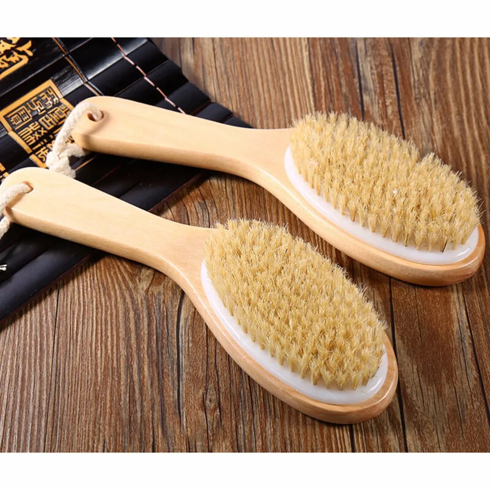 A pair of natural wooden body brushes with light yellow bristles are shown on a wooden surface.