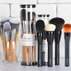 A collection of various professional makeup brushes in different sizes and colors displayed against a white brick background.