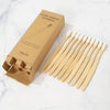 A box of eco-friendly bamboo toothbrushes and several individual brushes are displayed on a white marble surface.