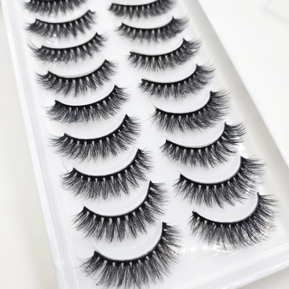 A tray of natural 3D mink false eyelashes displayed in a white plastic container.