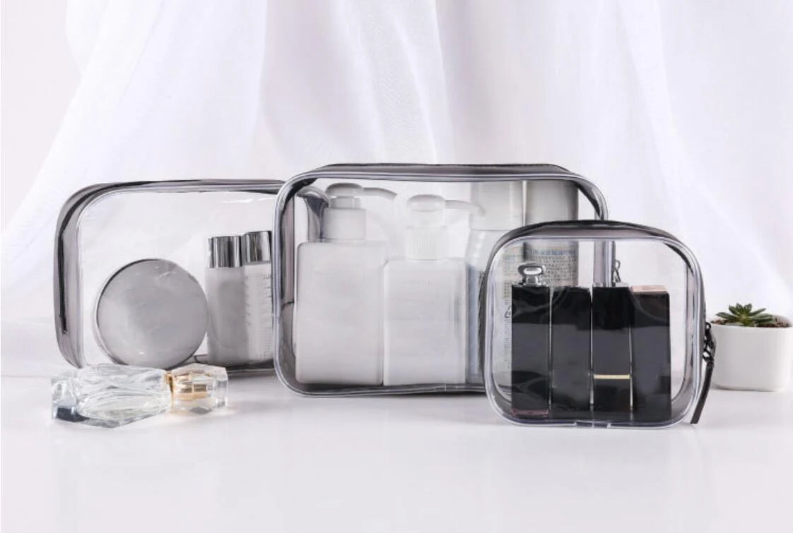 A clear waterproof travel cosmetic bag with compartments holding various toiletries and accessories.
