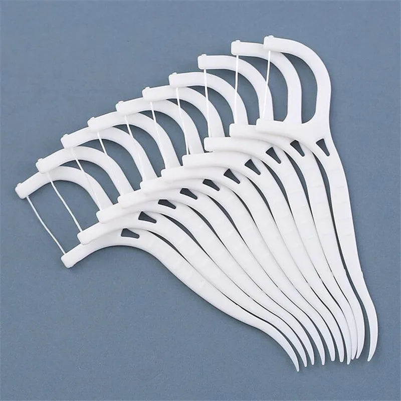 A bulk set of white disposable dental floss picks arranged in a fan shape.