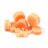 A collection of flexible silicone double flared ear tunnels in a light peach or orange color.