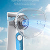 A white handheld mesh nebulizer device is shown with a clear mouthpiece, against a light blue cloudy background.