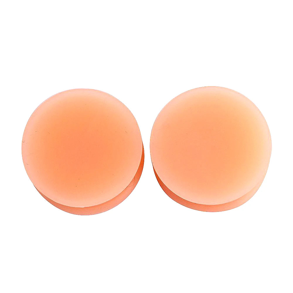 A pair of flexible silicone double flared ear tunnels in a light peach or orange color.