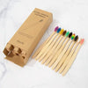 A box of natural bamboo toothbrushes for adults with individual brushes displayed on a white marble surface.