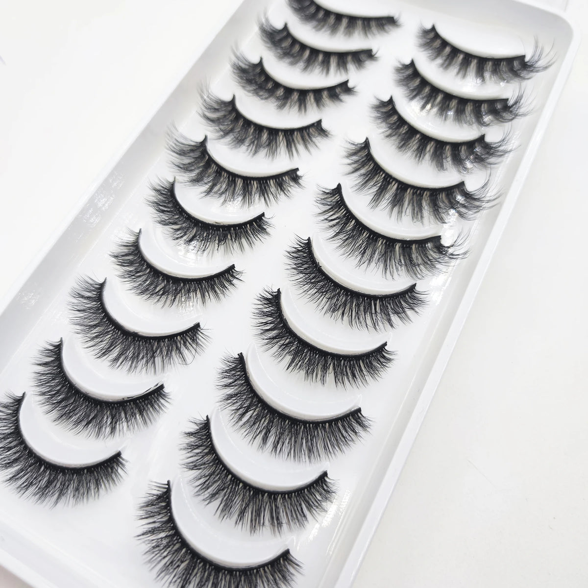 A display of natural 3D mink false eyelashes in various styles arranged in a white tray.