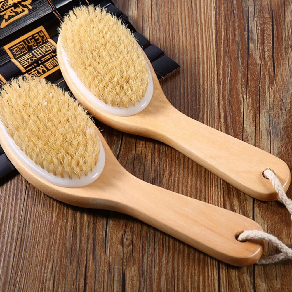 A pair of natural wooden body brushes used for dry brushing and exfoliation are shown on a wooden surface.