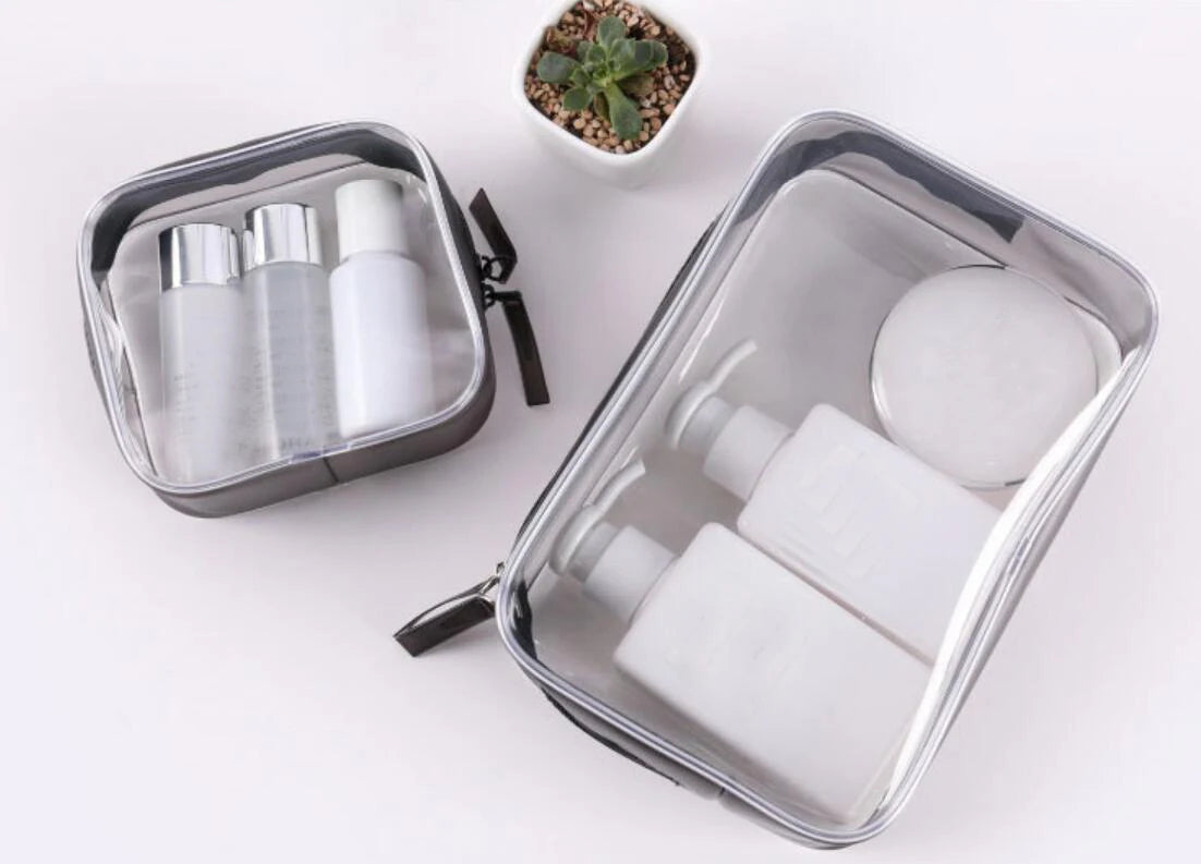 A clear waterproof travel cosmetic bag containing various white tubes and bottles for toiletries.