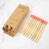 A box of natural bamboo toothbrushes and a set of 20 individual brushes are displayed on a white marble surface.