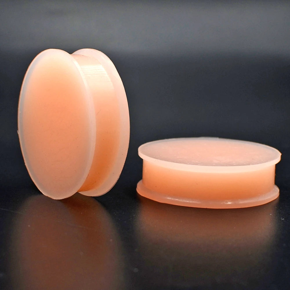 A pair of flexible silicone double flared ear tunnels in a light peach color.