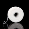 A roll of white mint flavored dental floss on a black reflective surface.