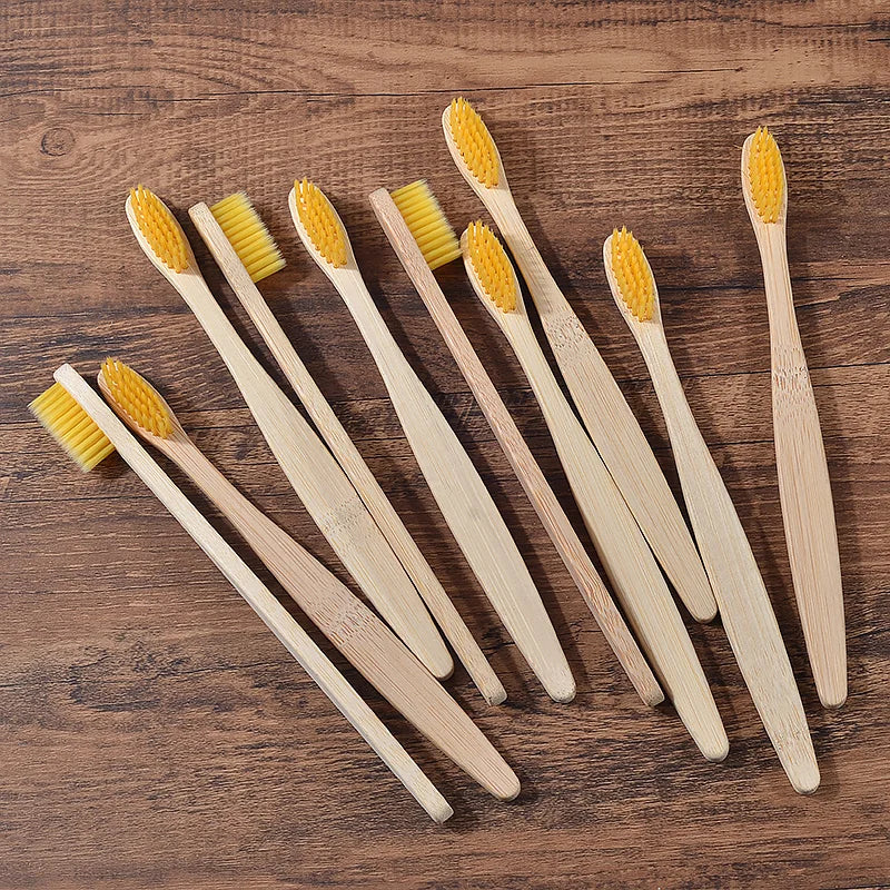 Un set de dix brosses à dents en bambou avec des poils jaunes, disposées sur une surface en bois.