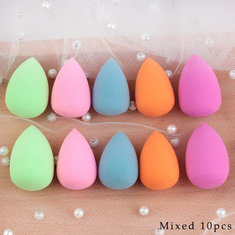A collection of ten pink and orange makeup sponge puffs arranged in a row on a light background.