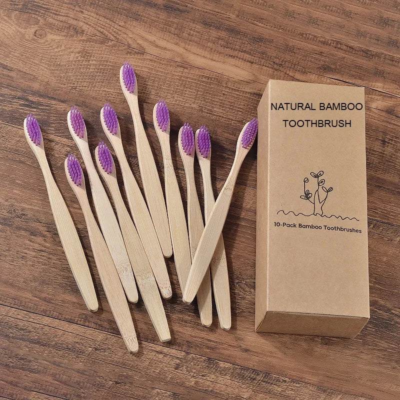 Une boîte contenant dix brosses à dents en bambou naturelles posées sur une surface en bois.