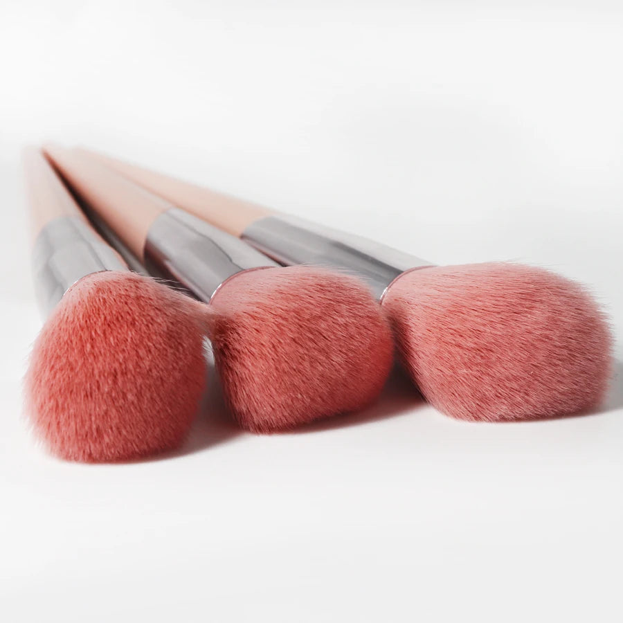 A set of pink angled cheek blusher makeup brushes with silver handles.