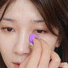 Close-up of a hand applying purple makeup to the skin with a flawless makeup sponge puff