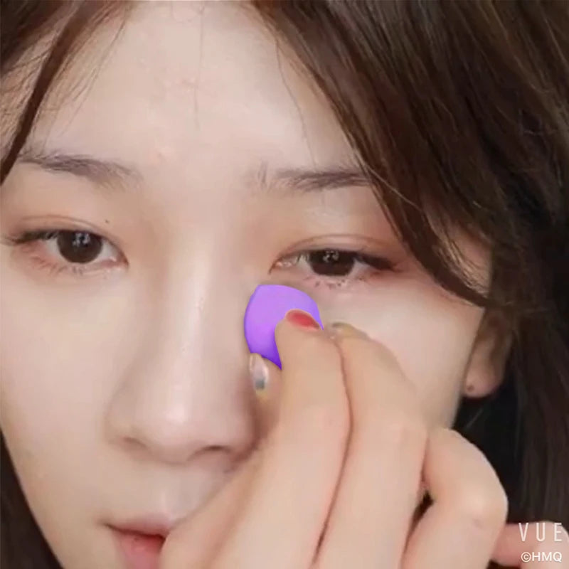 Close-up of a hand applying purple makeup to the skin with a flawless makeup sponge puff