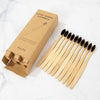 A box of natural bamboo toothbrushes and a set of 20 wooden toothbrushes on a white marble surface.