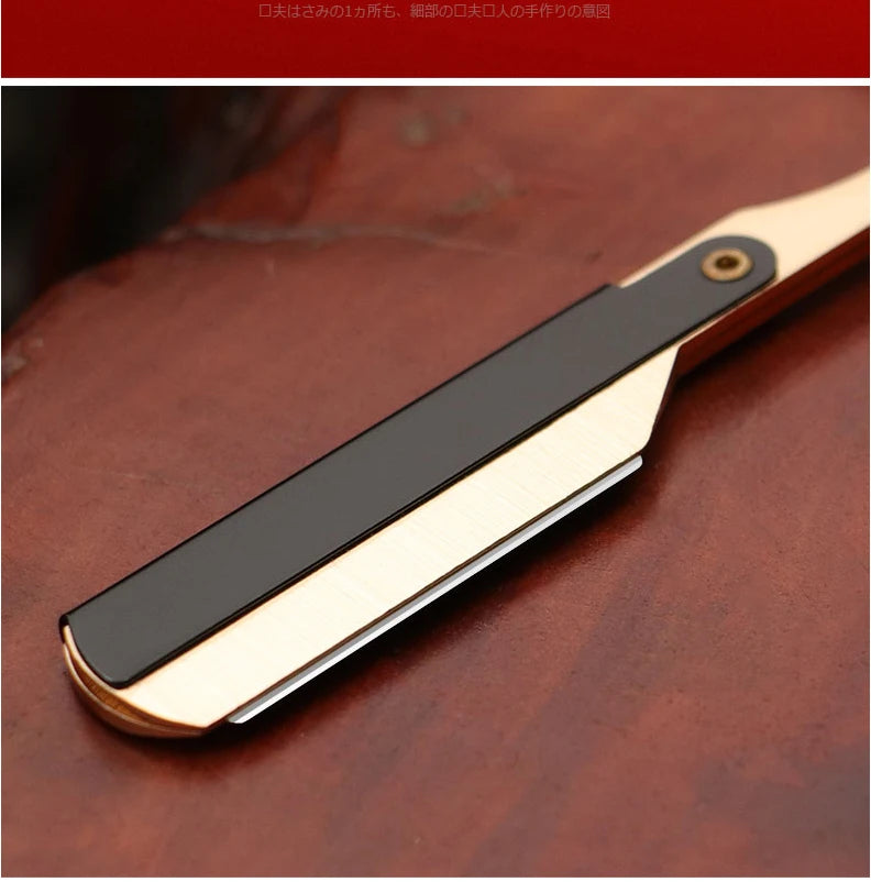 A professional straight edge barber razor with a black blade and gold accents resting on a dark wooden surface.