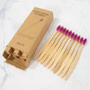 A box of natural bamboo toothbrushes and a set of 20 individual brushes on a white marble surface.