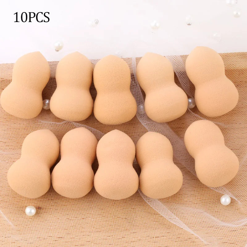 Ten peach-colored makeup sponge puffs arranged in a row on a sheer fabric background.