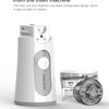 A white nebulizer unit and a separate medicine cup are shown on a surface.