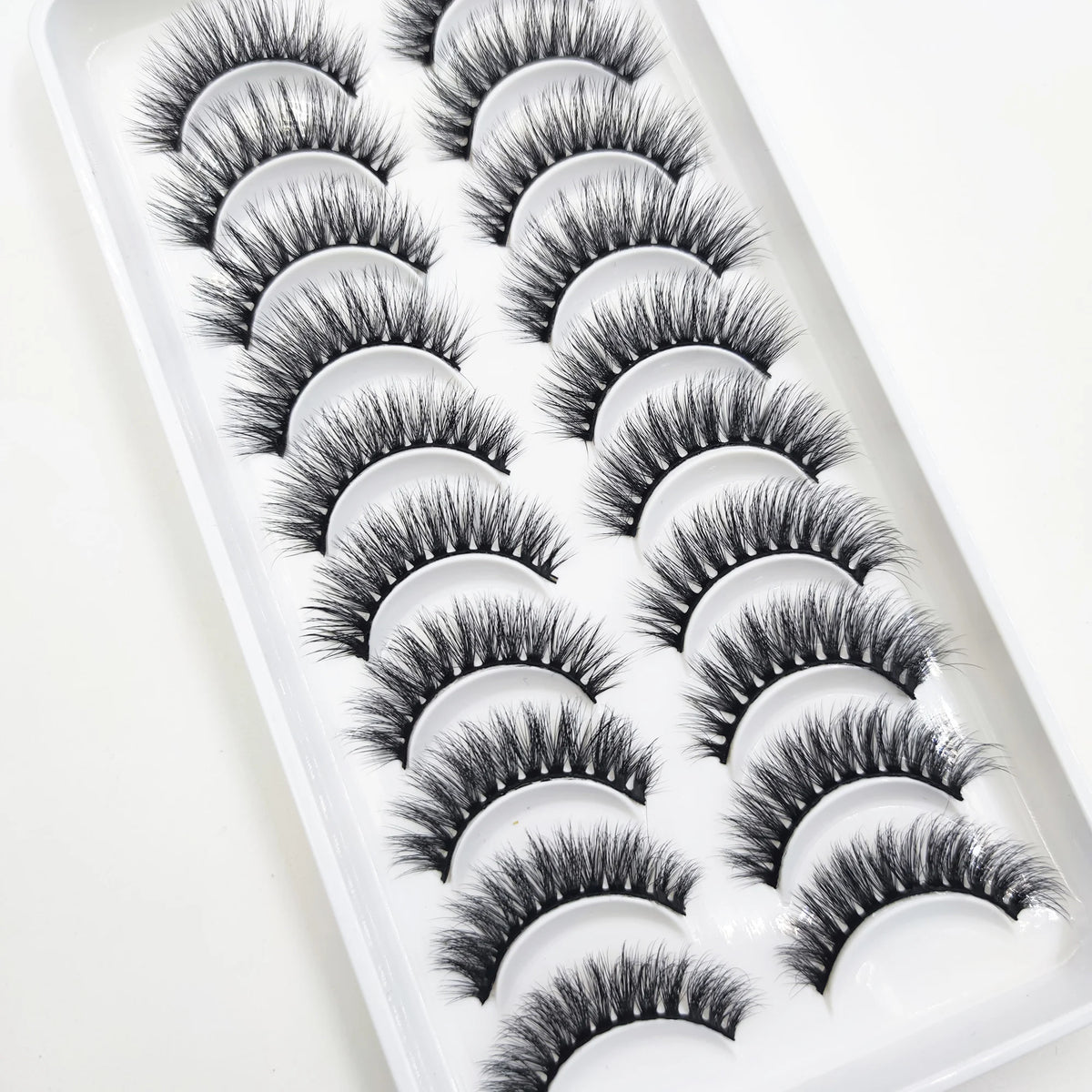 A plastic tray filled with various styles of black mink false eyelashes for eye makeup.