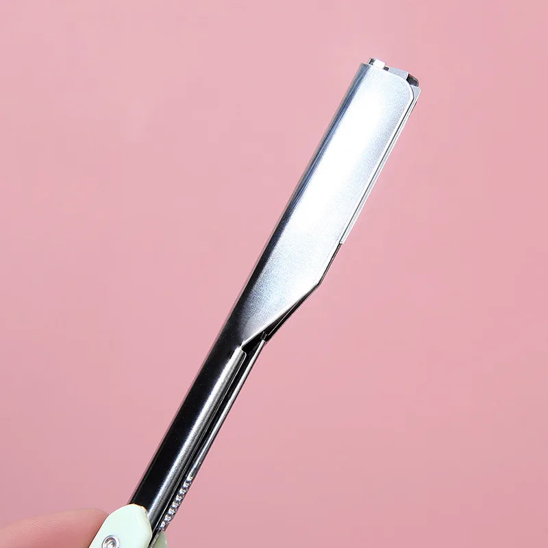 A silver folding straight razor shaver with a black handle is shown against a pink background.