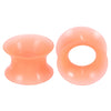 A pair of translucent peach silicone ear tunnels and plugs.