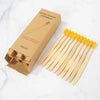 A box of natural bamboo toothbrushes and a set of 20 wooden toothbrushes on a white marble surface.