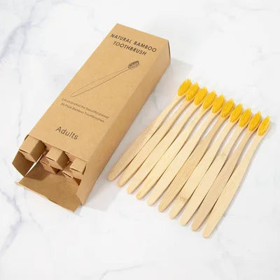 A box of natural bamboo toothbrushes and a set of 20 wooden toothbrushes on a white marble surface.