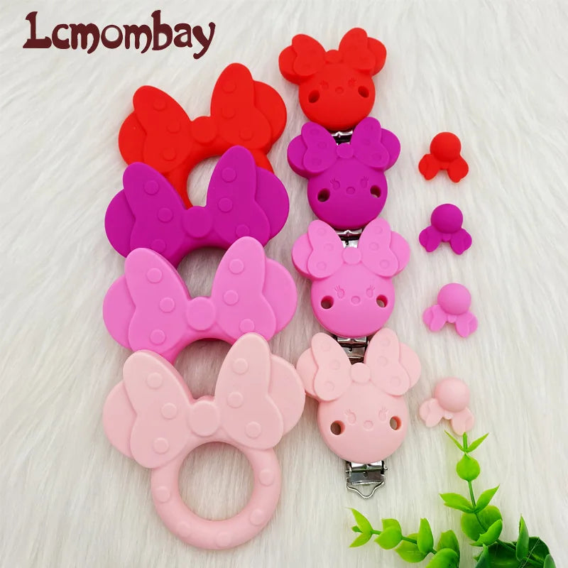 Collection de perles de tétons en silicone roses et rouges pour le soin oral du bébé, présentées sur fond blanc.