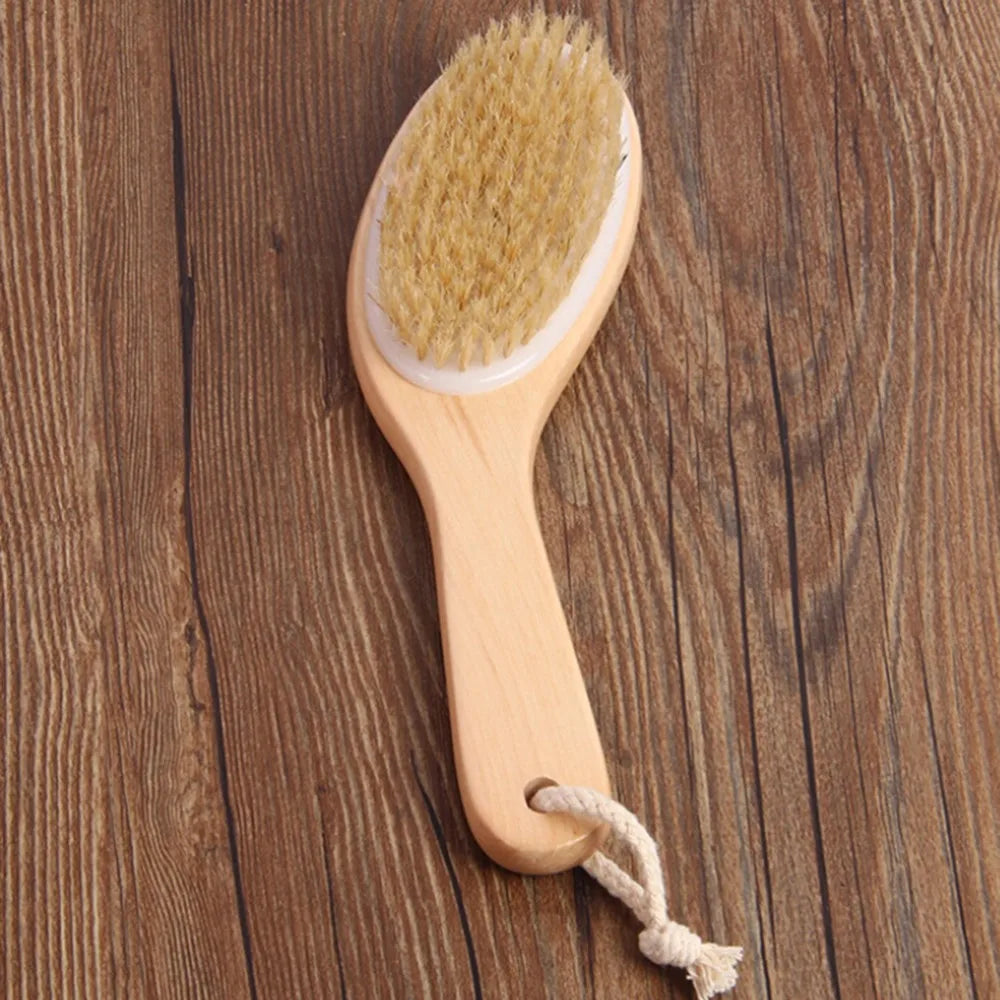 A natural wooden body brush with light yellow bristles is shown on a wooden surface.