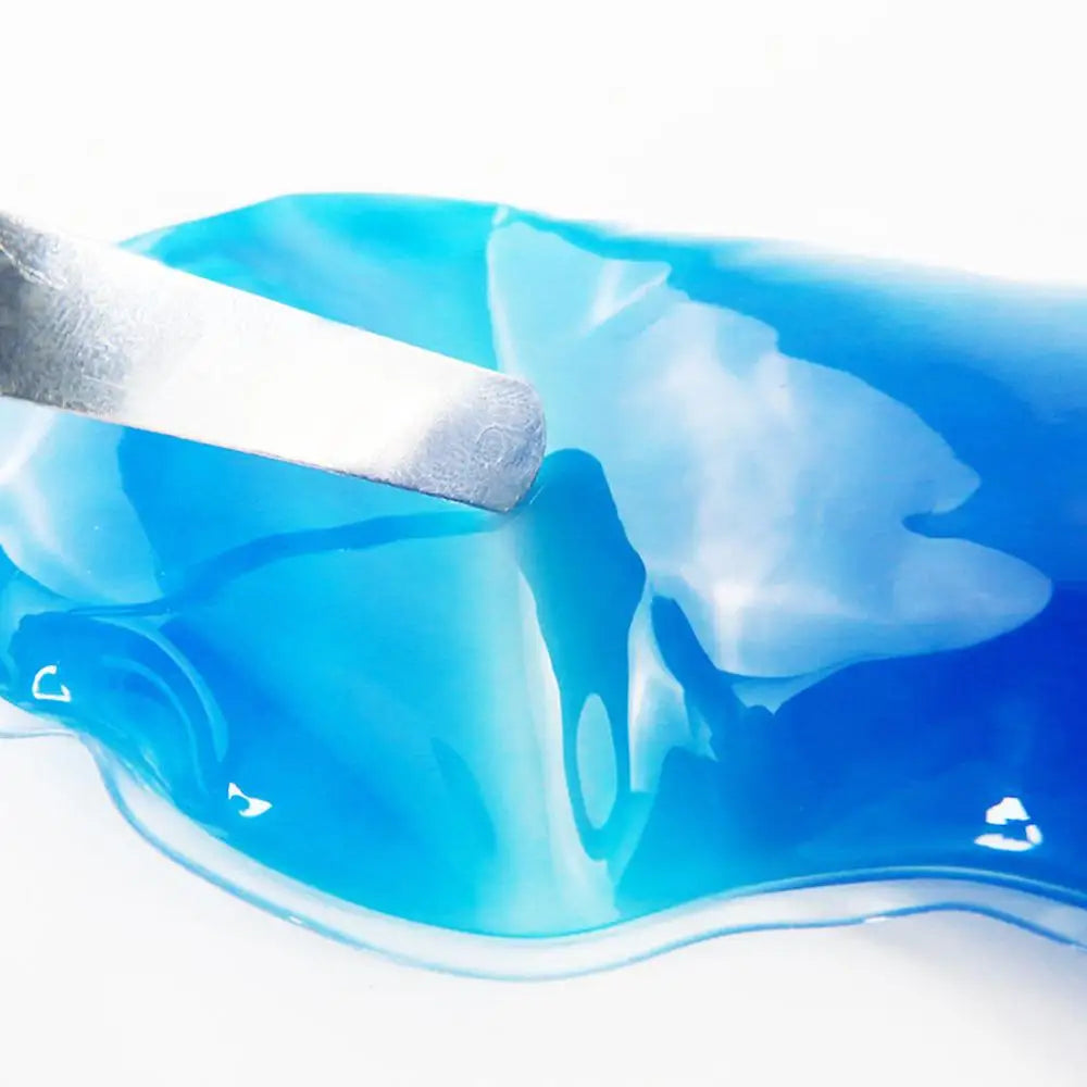 Un masque de sommeil bleu et glace est appliqué sur la peau avec un applicateur blanc.
