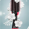 A black hot air brush hair dryer with pink accents surrounded by white roses and leaves.