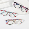 Un par de elegantes gafas de lectura florales anti-luz azul con monturas de color púrpura y rosa multicolores sobre una super