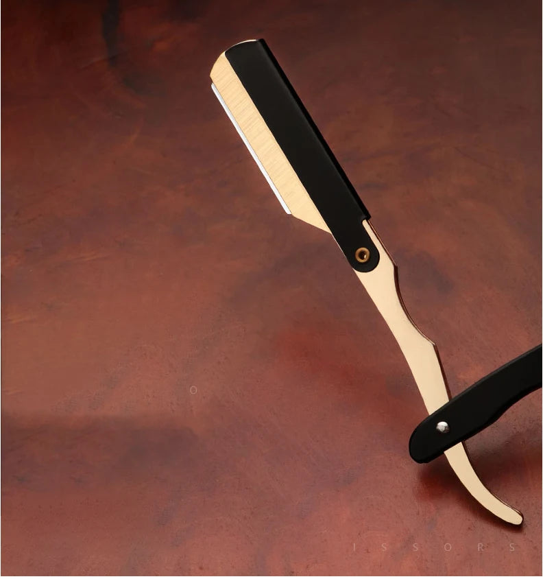 A professional straight edge barber razor with a light wood handle and black blade rests on a dark brown surface.