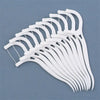 A collection of white dental floss picks arranged in a fan shape on a gray background.