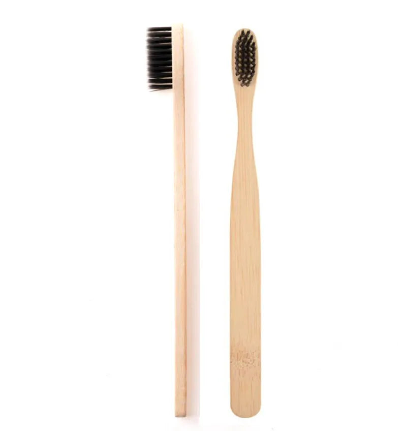 A natural bamboo toothbrush with dark bristles is shown standing vertically on a white background.